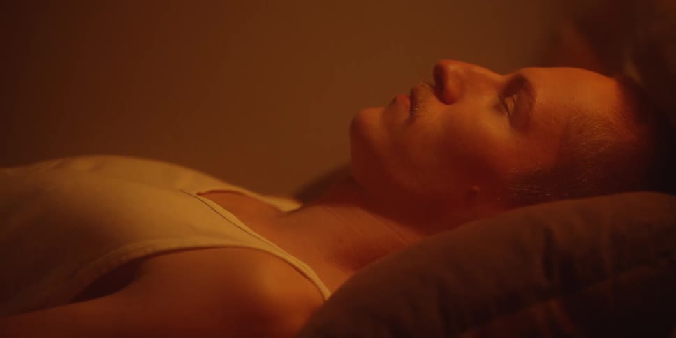 Person lying on a pillow under warm lighting with face in profile and eyes closed