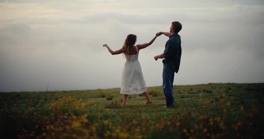 The man and woman dance on the green field