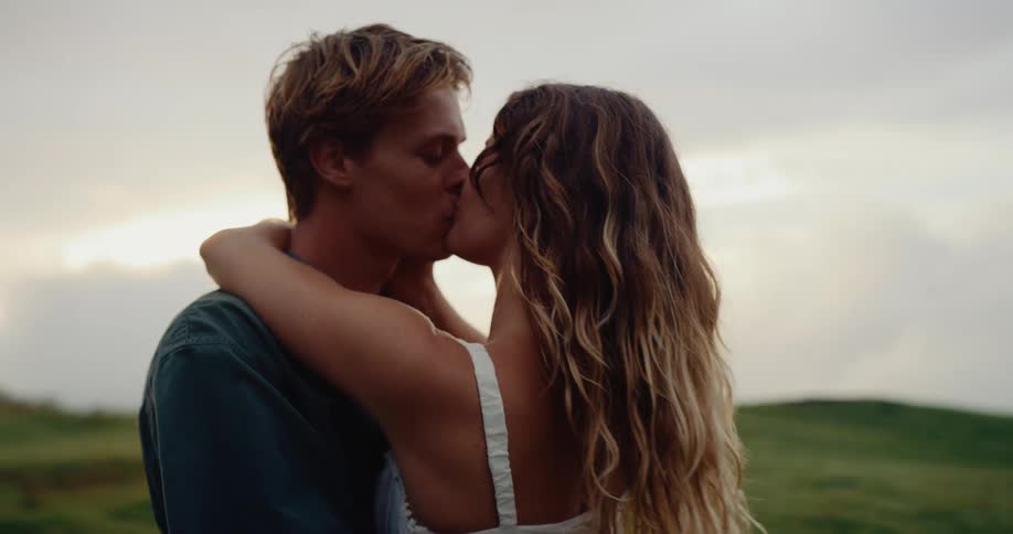 Couple standing on a slope kiss each other on a summer day