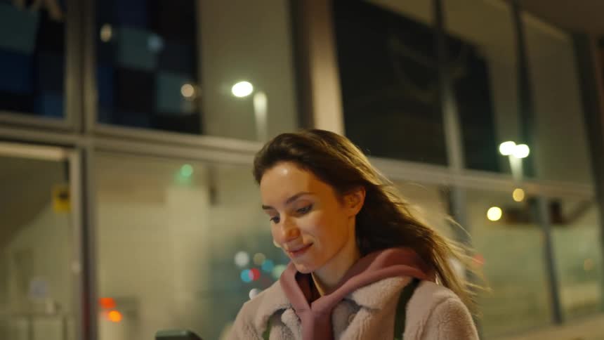 Woman walks on a city street texting on her phone