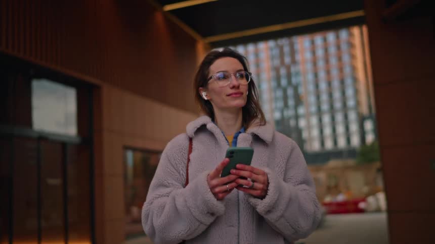 A woman walking outdoors with a phone