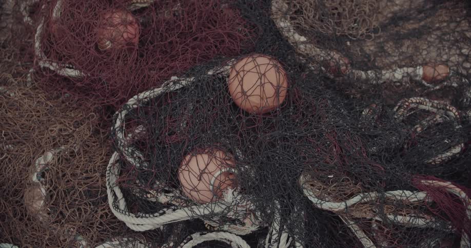 Dark fishing nets with circular floats intertwined on a light surface