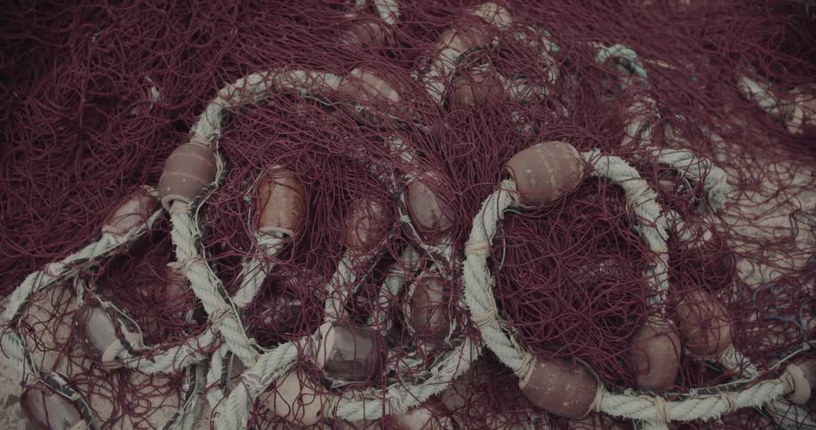 Red fishing nets with circular floats stacked on a light surface