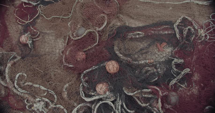 A tangled pile of old variously colored fishing nets is interspersed with small flotation buoys