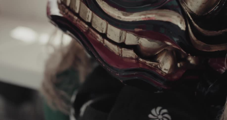A closeup shot captures the intricate details of a traditional japanese lion mask showcasing its dark sculpted face and prominent gold teeth the mask moves rhythmically opening and closing its mouth to reveal a deep red interior