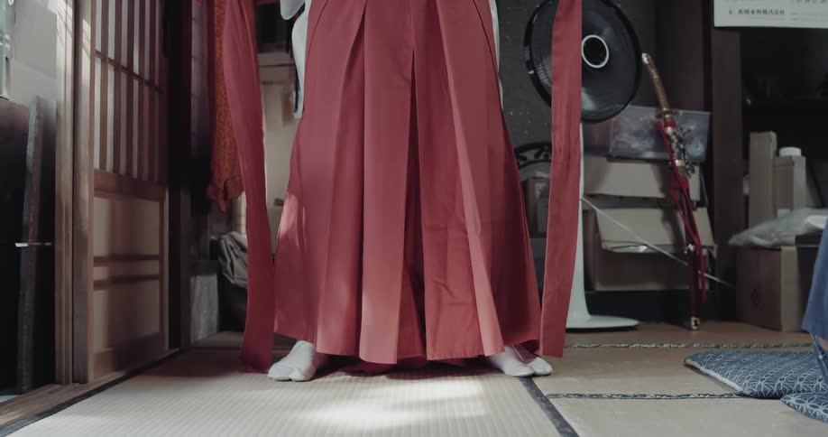 Female person standing in a room next to a door wearing a red skirt and white socks indoors during day time