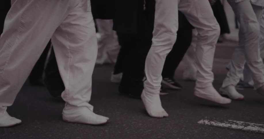 People dressed in white dancing on an urban street during a group performance