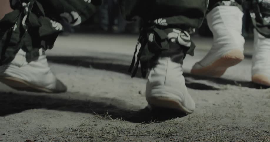 Closeup shots of dancers feet wearing traditional white japanese tabi boots on a dirt ground the rhythmic jumping and stepping motion of the dancers is captured during an outdoor night event