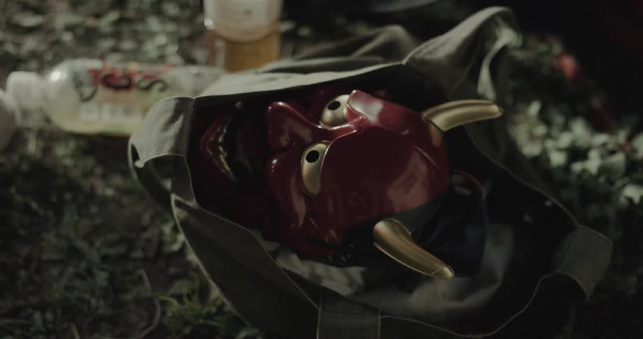 Young devilthemed figurine head placed inside a bag on the floor indoors at midday