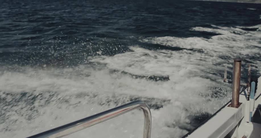 White wake churns intensely behind the stern of a boat moving across dark blue water