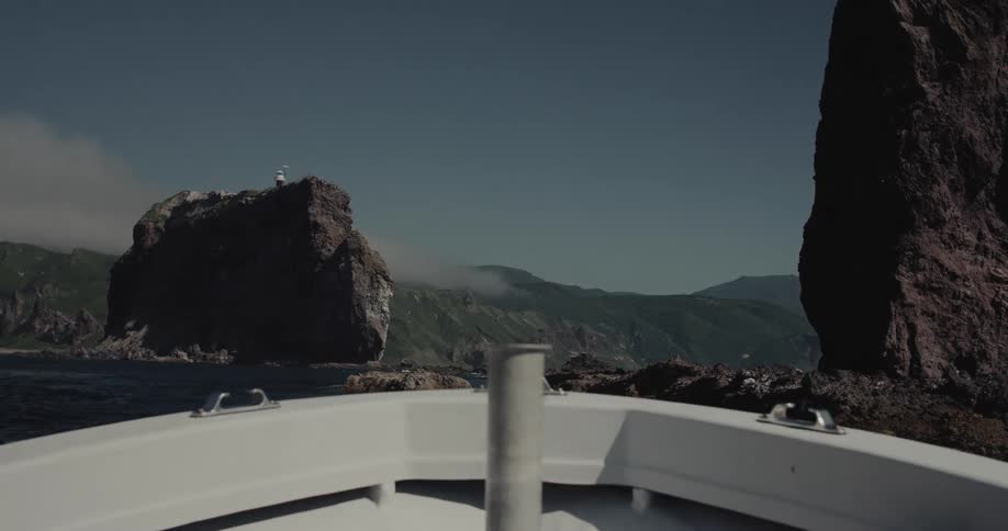 Front view of a boat moving through the sea with rocks in front