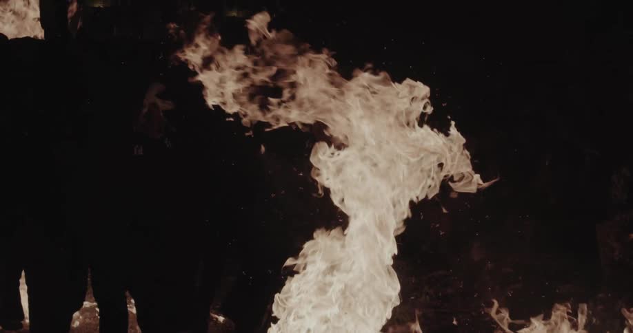 People running near intense flames in an outdoor nighttime setting