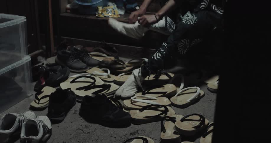 A person selects a pair of shoes from a pile puts them on and walks away