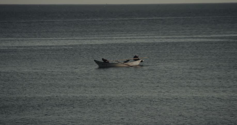 Small boat navigating calm sea away from the coast