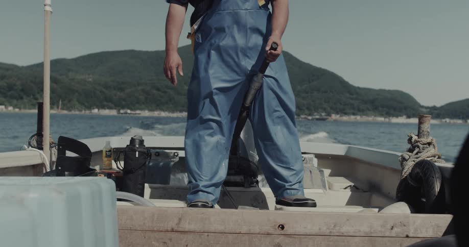 Man holding a lever on a moving boat in the ocean