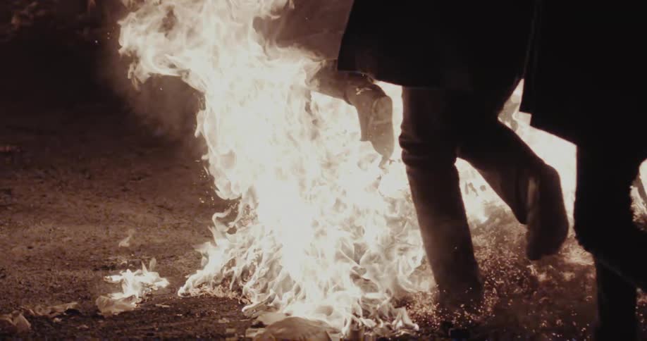 Legs walking near intense flames on the ground