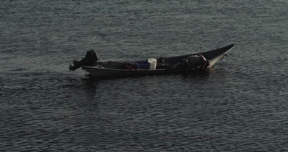 Man fishing in a small canoe on a calm sea
