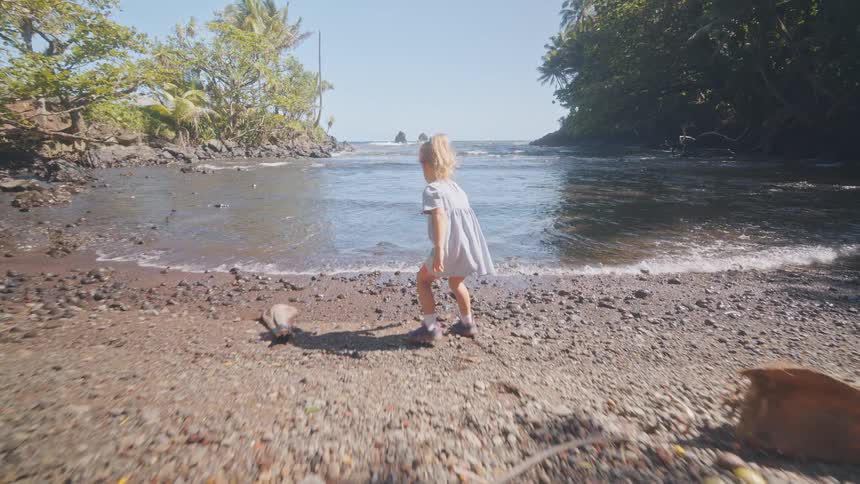 The girl walks close to the water and backs off