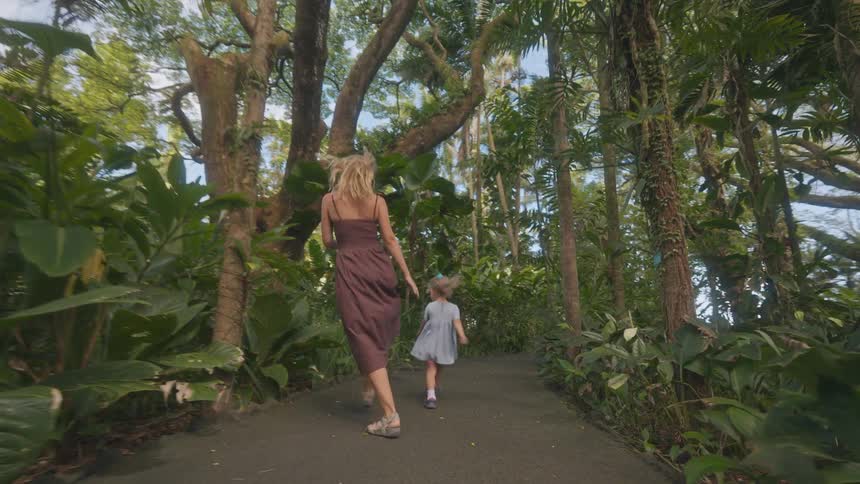 A mother and child running and having fun along a forest path the woman wearing sunglasses as she continues enjoying the playful moment with her kid