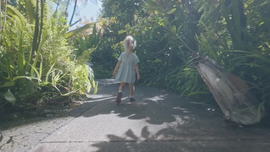 Little girl walking on a path through a tropical forest looking around
