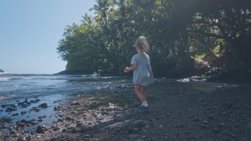The girl is playing with rocks on the shore