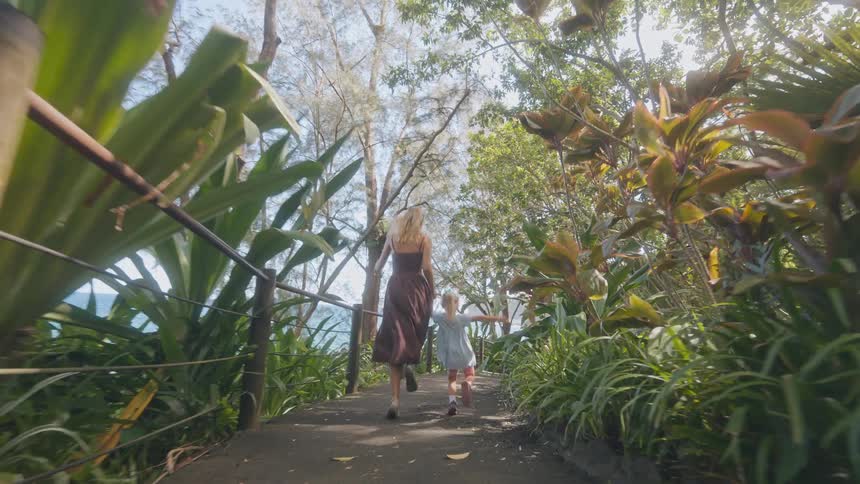 The woman holds hands with her daughter and run on the trail