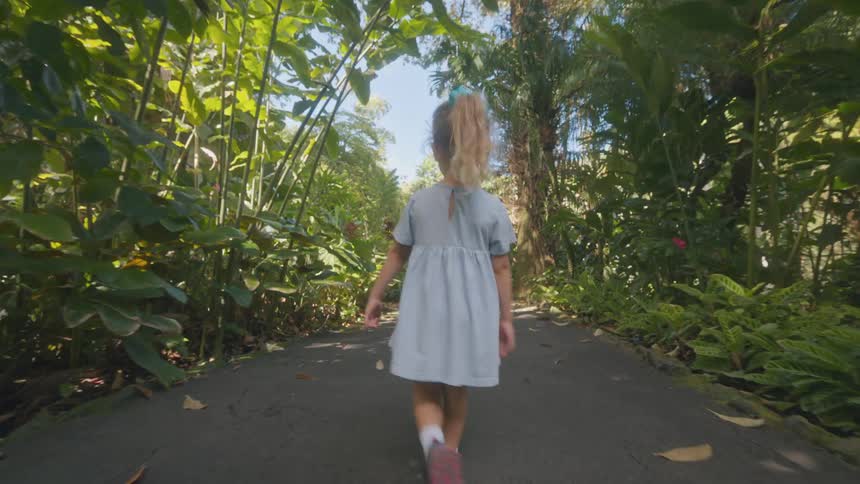 A child walking along a woodland path at midday enjoying her stroll while wearing a blue gown her long hair flowing as she moves