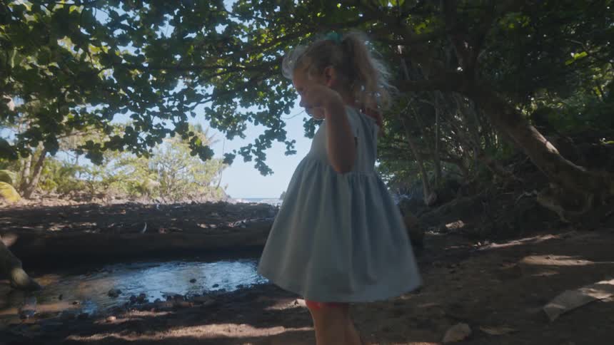 The girl is playing by a small creek