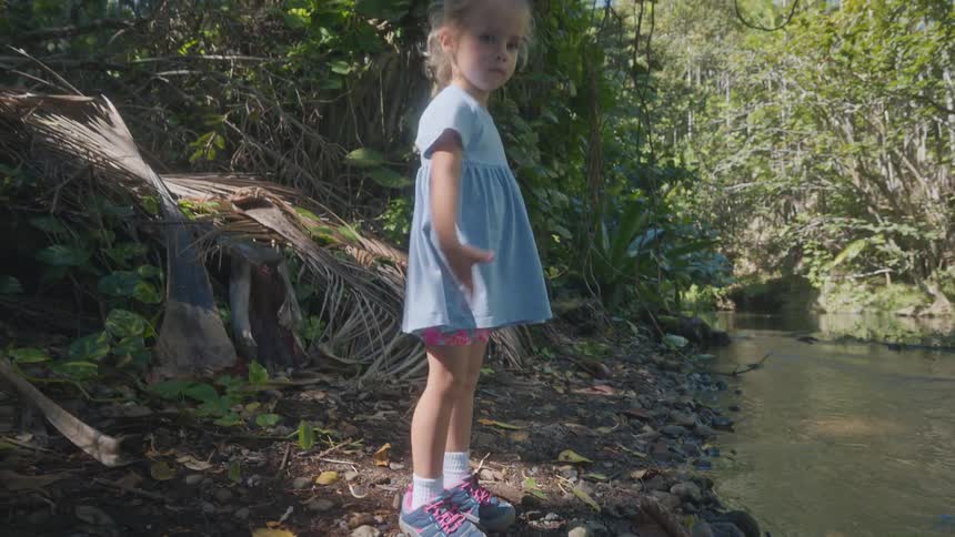 A child playing on the bank of a river