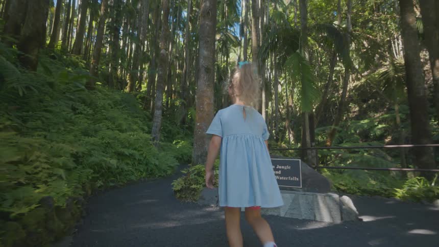 The girl walks on the trail past signs in the park