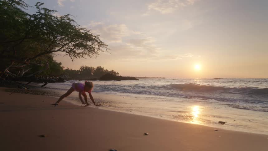 Little girl playing in the sand on the beach at dusk