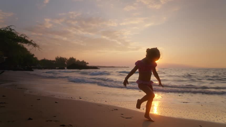 The girl kicks around the sand on the beach