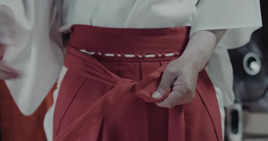 Hands tying a red piece of fabric from a costume around the waist