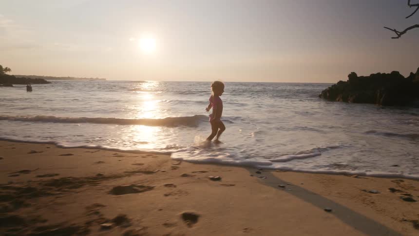 The girl runs and splashes in the water while swinging her arms