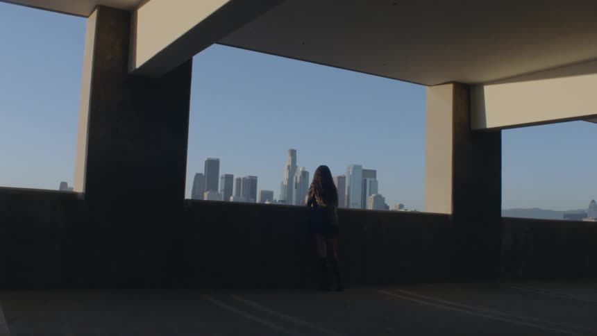 Person watches skyscrapers through opening in concrete structure
