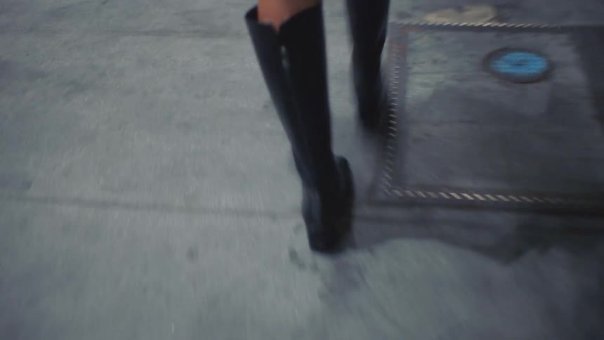 Black boots in motion on paved surface