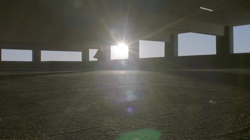 Woman walks in garage lit by intense sunlight