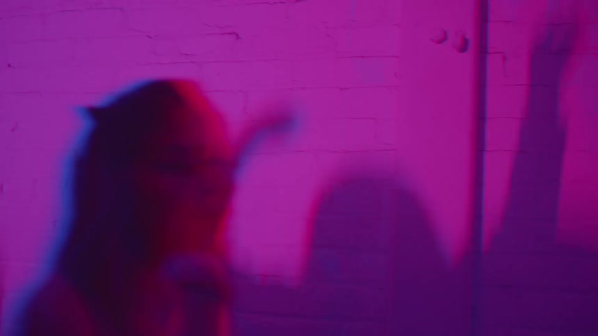 Silhouettes of people with raised arms under blue and purple lighting in an indoor setting