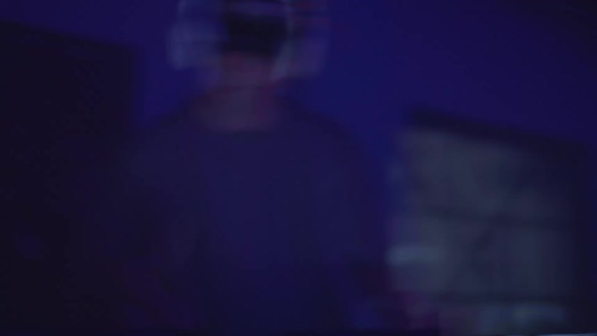Musician wearing headphones performs on a stage lit by colored lighting