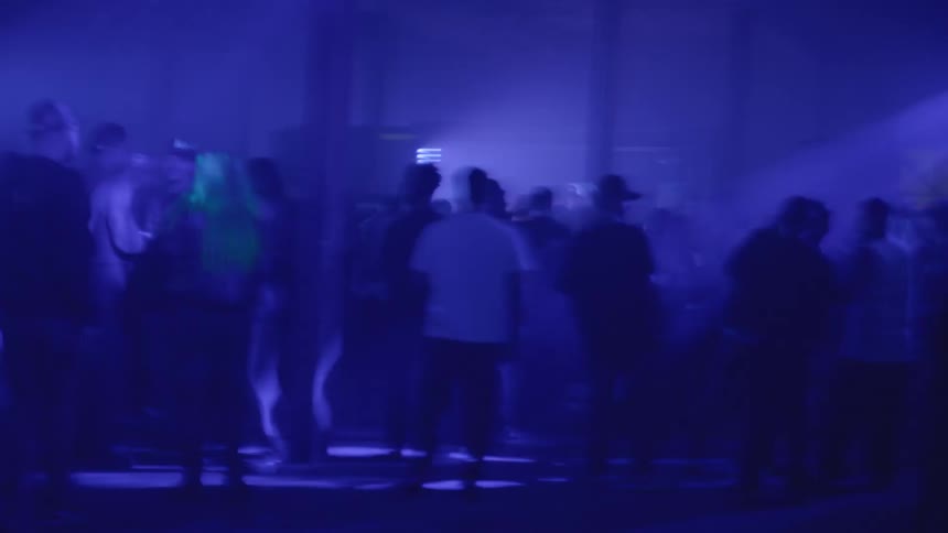 People are dancing in the dark club with flashing lights all over