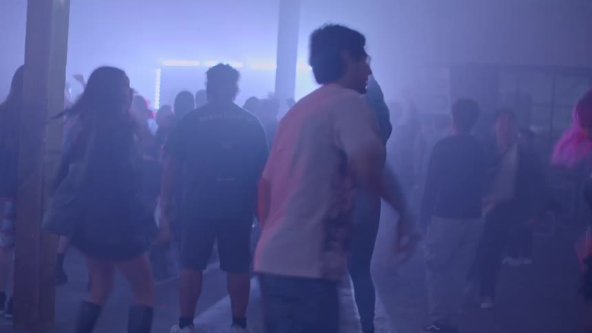 People dancing in an indoor venue with blue lighting and haze