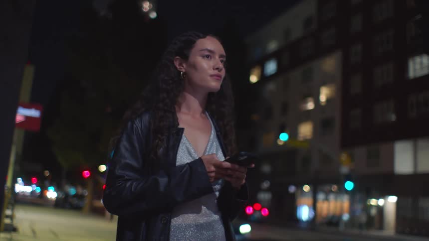 The woman looks at her cell phone in the city