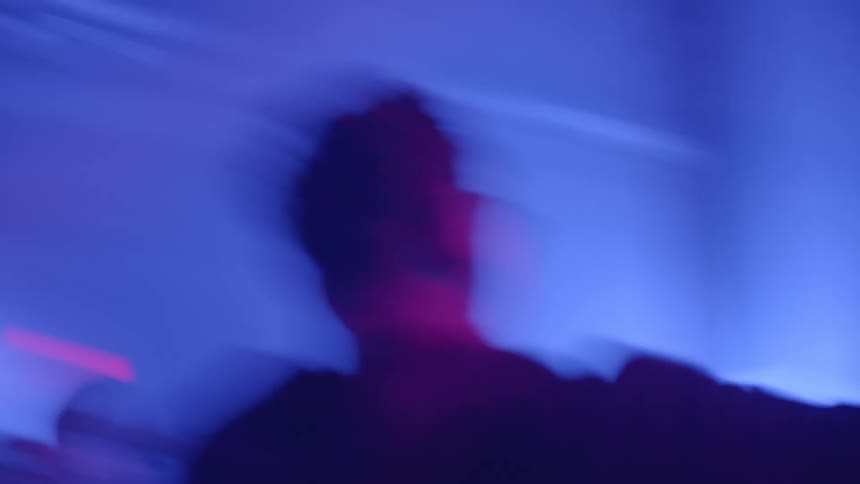 People dancing in a nightclub with blue lighting and a dark atmosphere