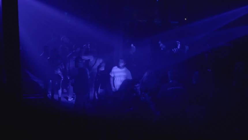 Lights flash in the dark club full of people