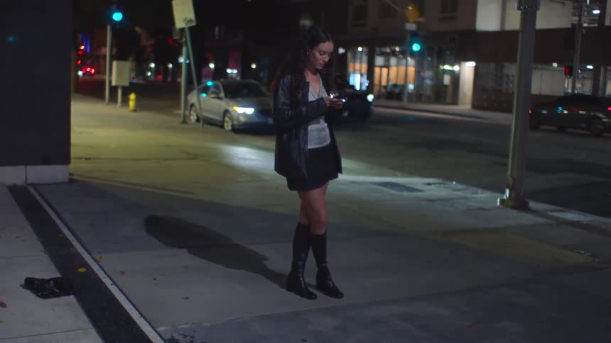 A woman standing on a sidewalk at night