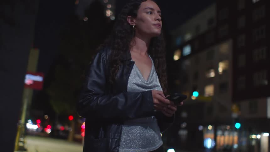 Woman waits on the sidewalk in a residential neighborhood at night before being joined by a friend