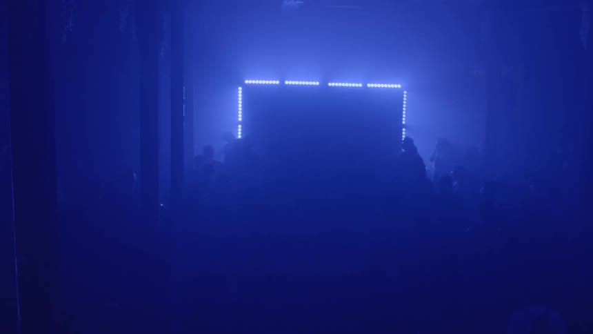 People attend a concert in a nightclub lit by blue lighting