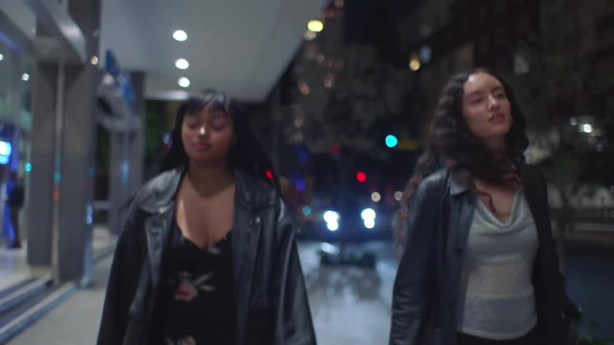 The friends smile while walking on the sidewalk