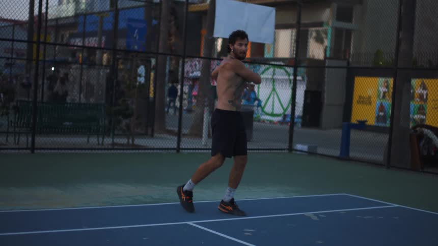 Man with a racket is hitting a tennis ball on a court