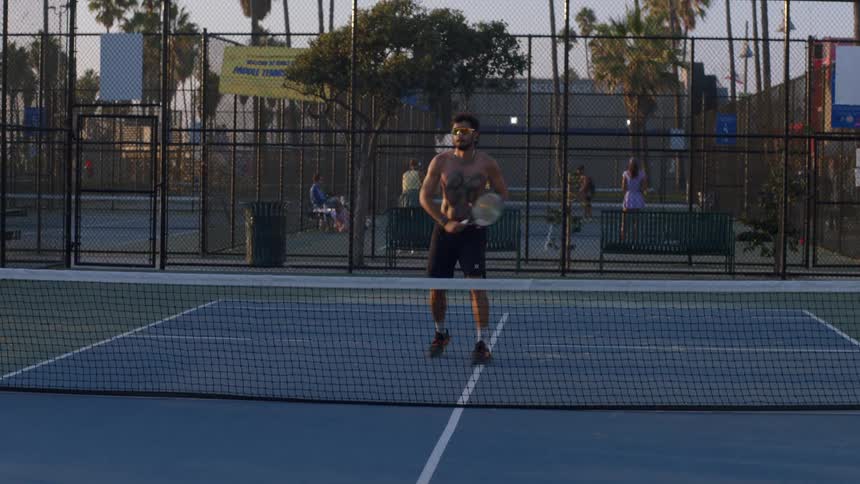 Player holds a racket and hits the ball on a sports court surrounded by fences